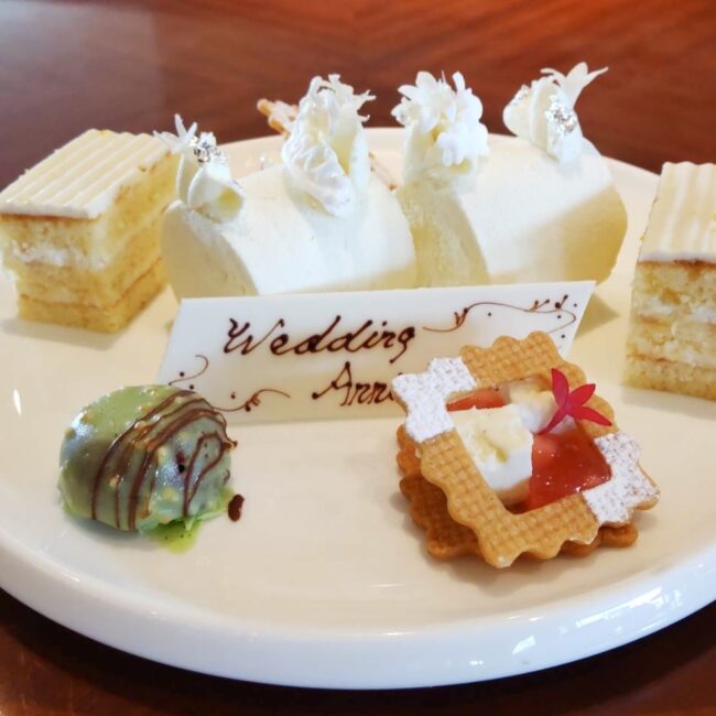 帝国ホテル「インペリアルラウンジ アクア」の記念日プレート。＋650円でアップグレードした手書きのメッセージチョコプレートと、美しく盛り付けられた一口サイズのケーキや焼き菓子の盛り合わせ。