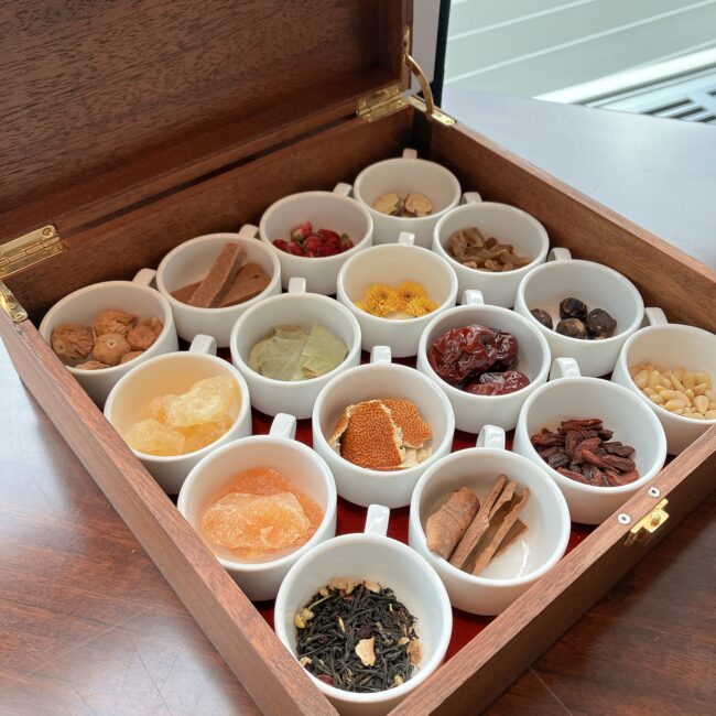 木製の箱に美しく陳列された、クコの実、なつめ、菊花、陳皮など10種類以上の色鮮やかな生薬や茶葉。