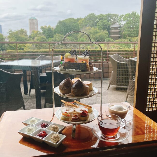 ホテル椿山荘東京「ル・ジャルダン」のアフタヌーンティーセット。三段スタンドの華やかなティーフーズとロンネフェルト紅茶。窓の外には広大な庭園と五重塔が広がる絶景。