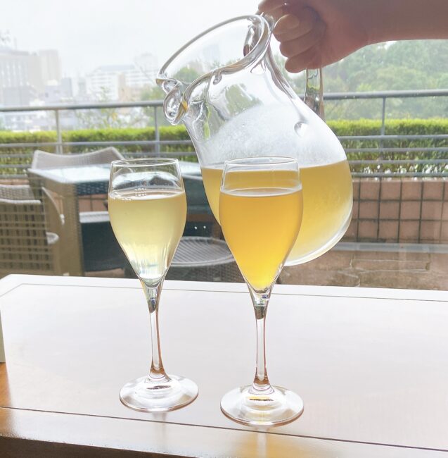 ホテル椿山荘東京「ル・ジャルダン」のラウンジで、ホテルスタッフが、ウェルカムティーの「ルジャルダン」を透明なグラスに丁寧に注いでいる。