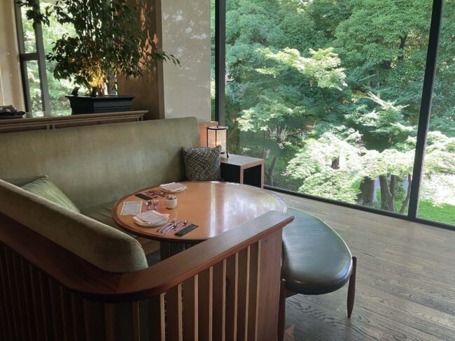 ラウンジ「Momiji(もみじ)」の窓際ソファ席。大きな窓の外には豊かな新緑が広がり、広々とした空間でゆったりとくつろげる様子。