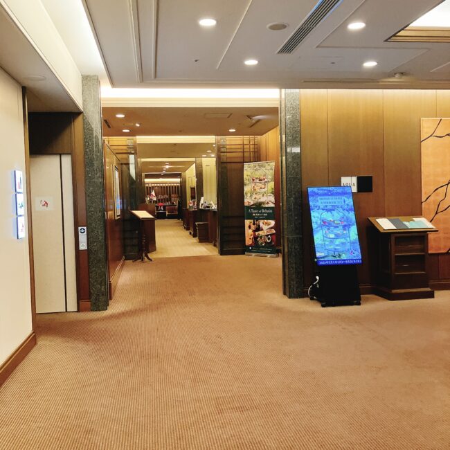 帝国ホテル東京の本館17階にある、インペリアルラウンジ アクアの入口。両サイドにはメニューや案内板が置かれており、奥へと続く通路が見える。