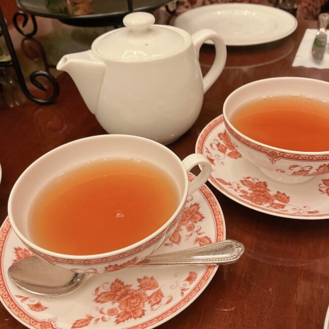 第一ホテル東京ロビーラウンジのアフタヌーンティーで提供された紅茶。ティーポットと、二つのティーカップ＆ソーサーが木目のテーブルに置かれている。カップには花柄の模様があしらわれており、温かい紅茶が注がれている。

