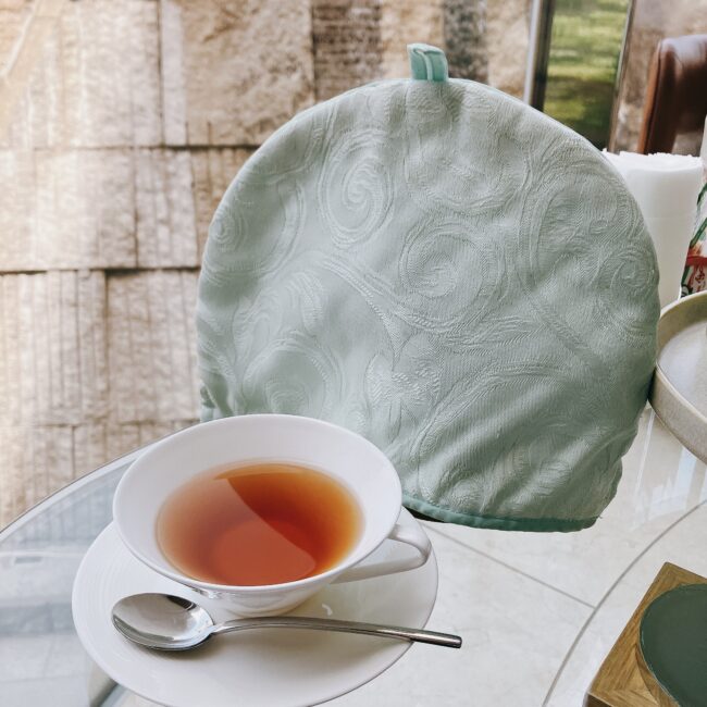 ザ・プリンス パークタワー東京で提供された紅茶。白いカップに注がれた紅茶の横に、ミントグリーンのティーコージーが置かれている。