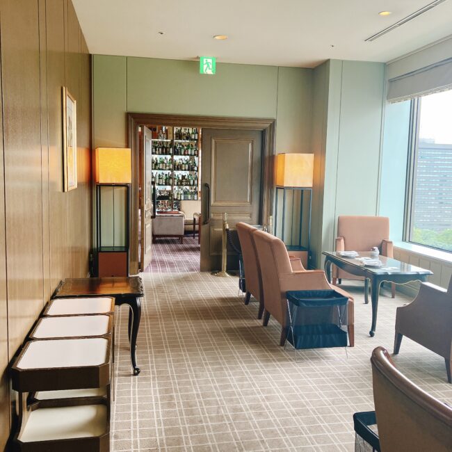 帝国ホテル東京 本館17階のインペリアルラウンジ アクアから、隣接するバーエリアへと続く入口の写真。奥の扉が開いており、棚には酒瓶が並んでいるのが見える。