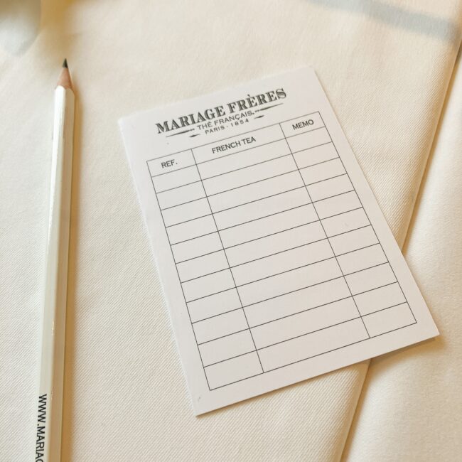 「MARIAGE FRÈRES」のロゴが入った白いメモ用紙。REF.、FRENCH TEA、MEMOの欄があり、紅茶の記録ができるようになっている。隣には鉛筆が置かれている。