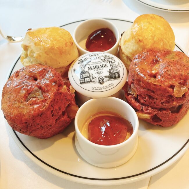 マリアージュフレールのアフタヌーンティーで提供されたスコーンプレート全体像。定番のプレーンスコーン「スコーンパリジャン」と、限定のピンク色の「ポム ドュ デジール」とリンゴのスコーンが計4個盛られ、中央にマルコポーロジャムが添えられている。