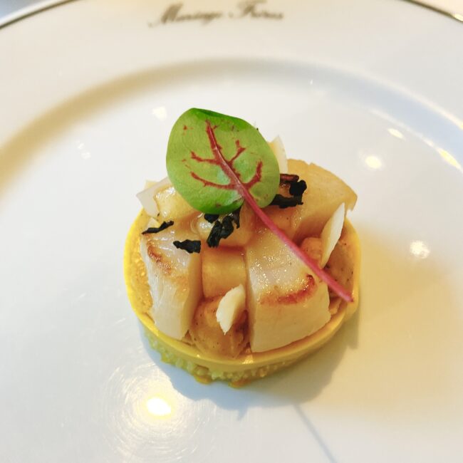 マリアージュフレールのアフタヌーンティーのセイボリー、「帆立のソテーとポティロンのフラン」。満月をイメージした黄色のフランの上に、ソテーした帆立とりんごが美しく盛り付けられている。