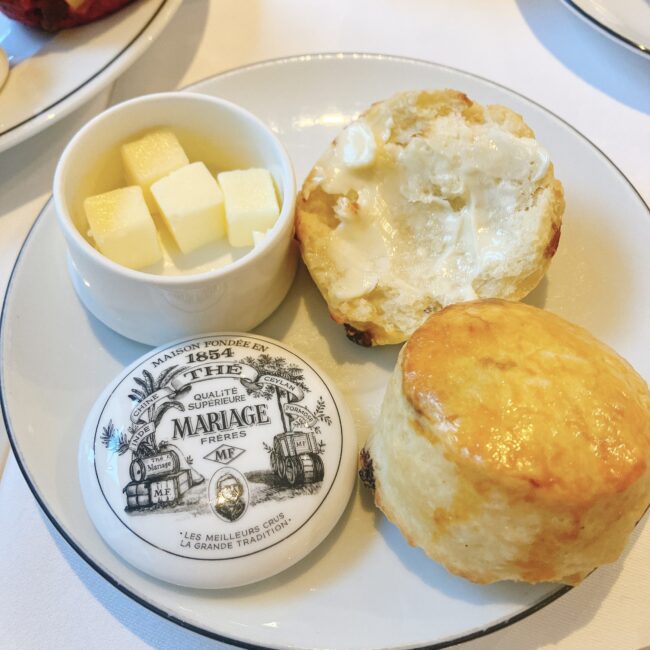 マリアージュフレールのアフタヌーンティーで提供されたバター。ロゴ入りの丸い陶器の蓋と、スコーン、カットされたフランス産バターが写っている。スコーンの一つにはバターが塗られている。