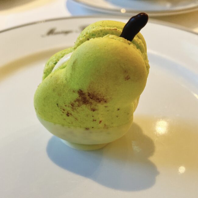 マリアージュフレール「フルムーンパーティー」のスイーツ、ルイボスティー「オトンヌ・ローズ」のマカロン。薄緑色と白色の洋梨の形をしており、チョコレートの軸が飾られた、凝ったデザインのマカロン。