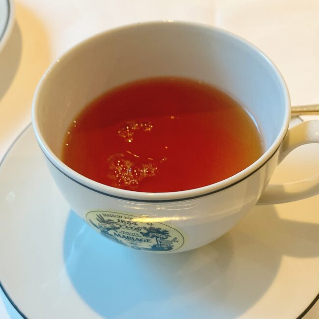 マリアージュフレールの白いティーカップに注がれた、赤茶色の紅茶「1854」。ジャスミンとアールグレイが香る爽やかなブレンドティーで、ブラックシルクよりも淡い水色。
