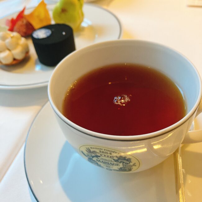 マリアージュフレールの白いティーカップに注がれた、濃い赤褐色の紅茶「ブラックシルク」。雲南の茶葉をベースにしたノンフレーバーティーで、キャラメルを思わせる風味がある。