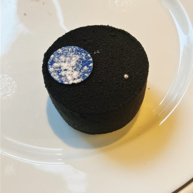 マリアージュフレールのスイーツ「月夜のフルムーン ケーキ オ テ プルーン ルヌ」。黒いビロード状のムース(夜空)に青い満月が飾られたチーズケーキの外観と、断面に現れた金柑コンフィチュール(月の光)の様子。