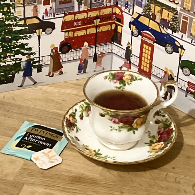 トワイニング アドヴェントカレンダー2025、3日目の「ロンドン アフタヌーン」。紅茶が注がれた花柄の英国風ティーカップと、ロンドンの街並みの背景。ミルクティーにおすすめの濃い目のブレンド。