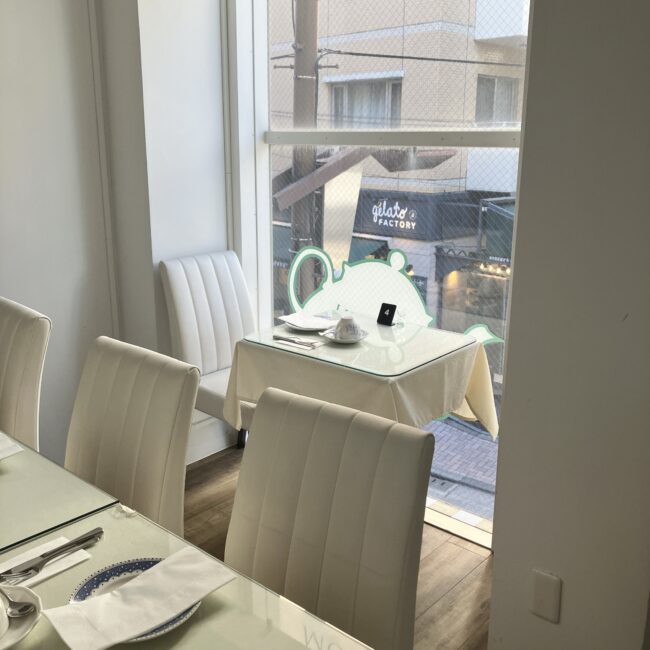 ジュリスティールームの窓側の特等席。おひとりさまに最適な一人用の小さなテーブル と白い椅子。外の景色が見えている。