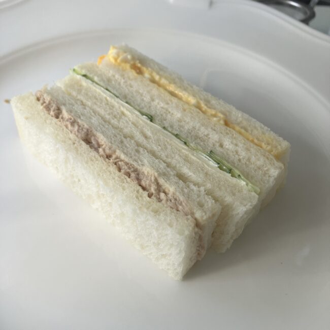 ジュリスティールームのアフタヌーンティーで提供されたフィンガーサンドウィッチ。パンの耳が落とされ、ツナ、卵、きゅうりの3層が縦に並んでいる。