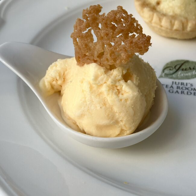 ジュリスティールームの自家製アイスクリーム。黄色いアイスクリームが一匙すくわれており、上にサブレの飾りが乗っている。