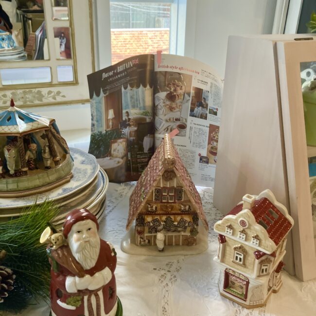 ジュリスティールームの店内のクリスマス装飾。サンタクロースやジンジャーブレッドハウス型の陶器のフィギュア、そして英国風アフタヌーンティーの雑誌が開かれている。