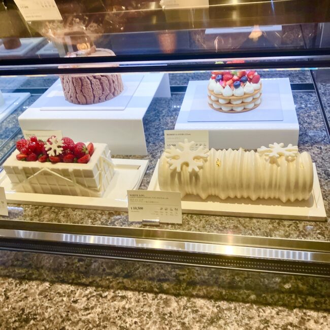 雪の結晶のチョコレートが飾られた、真っ白なリブ模様のクリスマスケーキ「ホワイトログ」など、芸術的なホールケーキの数々。