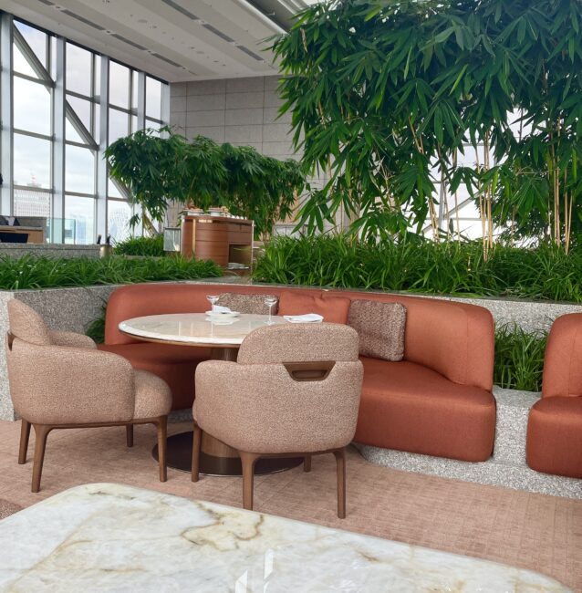 ピークラウンジ内側のゆったりとした曲線を描くソファ席。一段高いフロアにあり、背後の豊かなグリーンとモダンなインテリアが調和している。