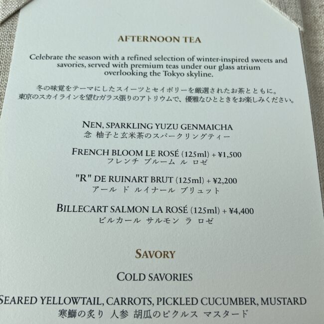 パークハイアット東京「ピークラウンジ」のアフタヌーンティーメニュー。ウェルカムドリンクとして「念(NEN) 柚子と玄米茶のスパークリングティー」が用意されており、追加料金で「"R" DE RUINART BRUT(アール ド ルイナール ブリュット)」などのシャンパンに変更可能なことが記載されている。