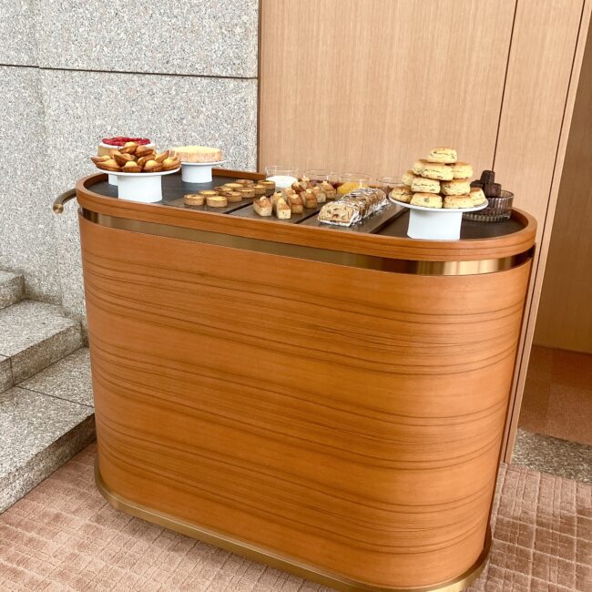 パークハイアット東京「ピークラウンジ」のワゴンサービス「CAKES FROM THE TROLLEY」の全景。柔らかな質感の木製ワゴンに、スコーン、マドレーヌ、カヌレ、タルトなどの焼き菓子が美しくディスプレイされている。