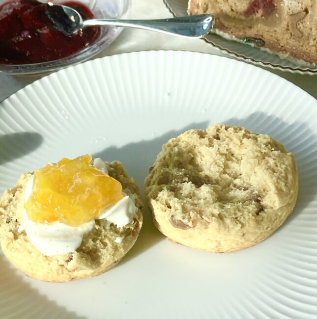 半分に割ったスコーンに、新しく提供されたクリームチーズとマーマレードをたっぷりと乗せた様子。クロテッドクリーム終了後の新しい楽しみ方として、軽やかで洗練された味わいを提案する一枚。