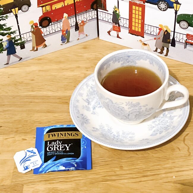 トワイニング アドヴェントカレンダー 2025、12月1日のレディグレイ開封写真。ティーバッグのタグに記載された「BREW FOR 1.5 MINUTES（1分半蒸らし）」の指示。英国風のティーカップに入ったレディグレイ。