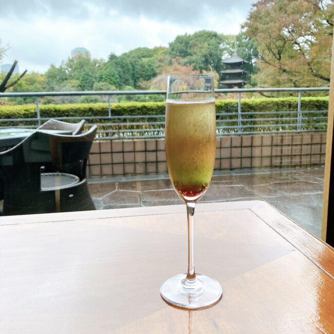 2022年椿山荘クリスマスアフタヌーンティーのウェルカムドリンク。赤と緑のコントラストが鮮やかなセパレートティーで、比重差を利用した美しい3層構造が特徴。背景に冬の庭園を臨むル・ジャルダンの窓際席にて撮影。