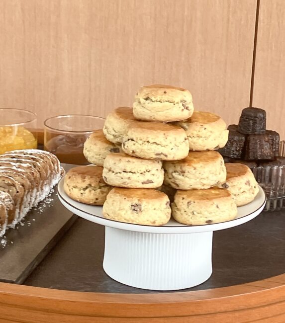 パークハイアット東京「ピークラウンジ」のトローリー上の焼き菓子接写。白いスタンドに山積みにされた自家製スコーン、奥にはカヌレ、左にはシュトレンが並ぶ