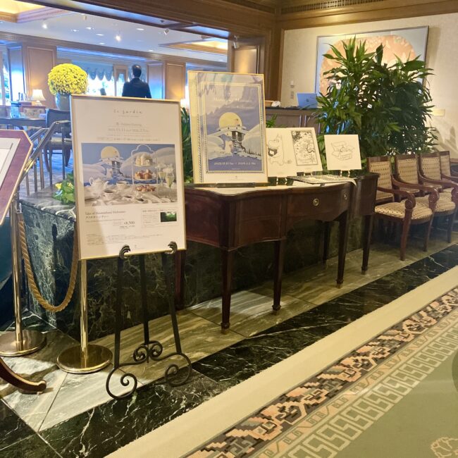 椿山荘東京「ル・ジャルダン」入口に設置されたムーミンアフタヌーンティーの告知ボードと、物語の世界観を伝える展示。高級感のある大理石の床とアンティーク家具が、今回のコラボの特別感を際立たせている。