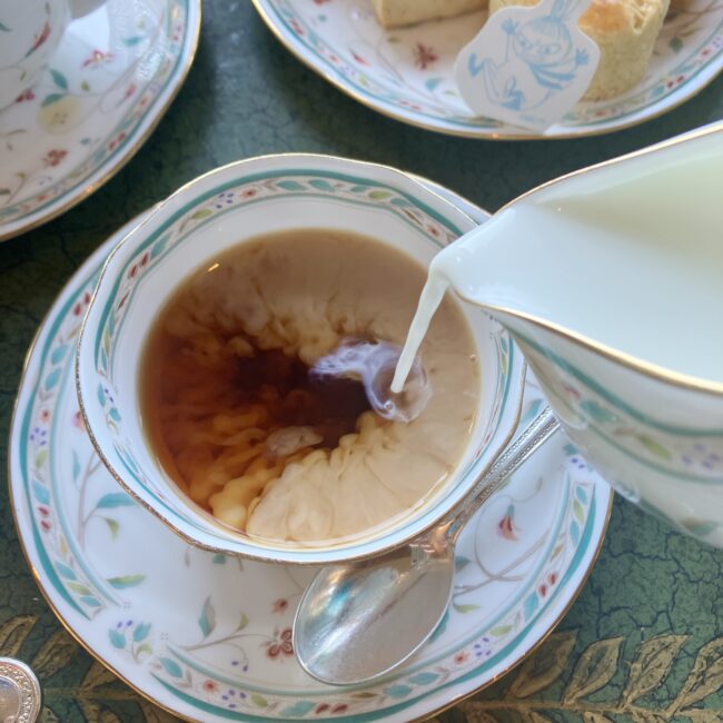 アフタヌーンティーの紅茶にミルクを注ぐ様子。カップの中で広がるミルクの対流。