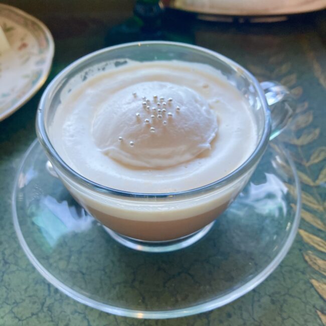 椿山荘「ル・ジャルダン」の限定ミルクティー「ホワイトポップミルクティー」。バニラ＆ペアの紅茶に、ポップコーンフレーバーのクリームと銀色のアラザンがトッピングされたアップ写真。