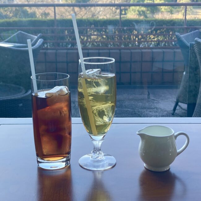 椿山荘の庭園を背景にした2種類のアイスティー。左はしっかりとした水色の「アイス セイロン」、右は黄金色に輝く本日のアイスティー「モルゲンソネ」。