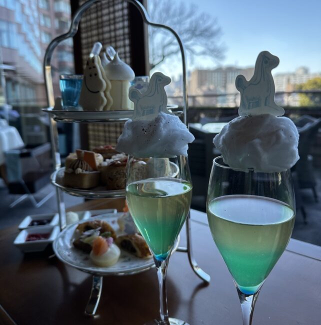 椿山荘ル・ジャルダンの特別ウェルカムドリンク。青、グリーン、黄色の3層が織りなすオーロラのグラデーションが美しく、背後の温かい紅茶との対比がこれからのペアリングの楽しみを予感させる。