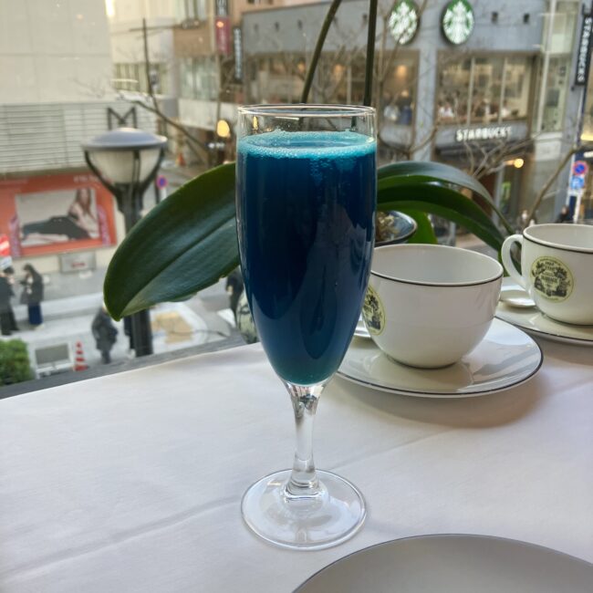 銀座松屋通り店の窓際で輝く、鮮やかな青色のティーモクテル「ノエル インペリアル」。