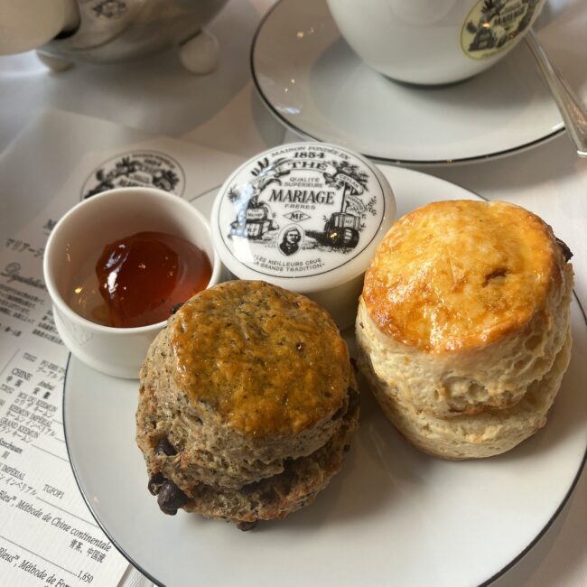 マリアージュフレール銀座松屋通り店のアフタヌーンティーで提供される2種類のスコーン。右はレーズン入りの「スコーン パリジャン」、左は店舗限定の紅茶「ウエディング インペリアル」を使用したチョコレートスコーン。奥には紅茶のジャム（ノエル アムール）とバターが添えられている。