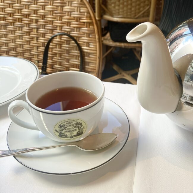 マリアージュフレールのアッサムティー「エセルウォルド (ETHELWOLD) Ref. T1539」。白磁のカップに満たされた、深く濃い赤褐色の水色（すいしょく）が、その力強いコクとモルティーな味わいを物語っている。ソーサーには銀のスプーンが添えられている。