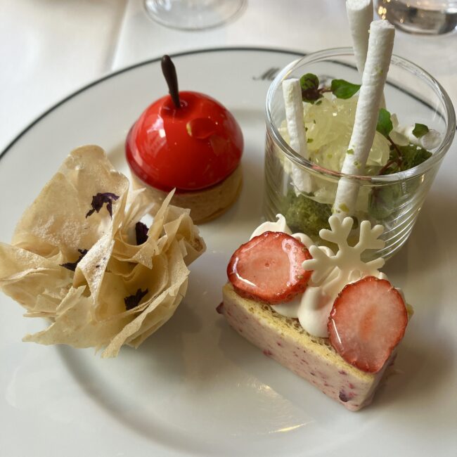 マリアージュフレール銀座松屋通り店のアフタヌーンティー「ROYAL FAIRY TEAS」のスイーツ4種盛り合わせ全景。左から時計回りに、パリパリの生地の「クルスタッド」、真っ赤なリンゴ型の「タルトポンム」、グラスに入った文旦の「ヴェリーヌ」、苺が乗った「ビュッシュ フレンチ ノエル」。