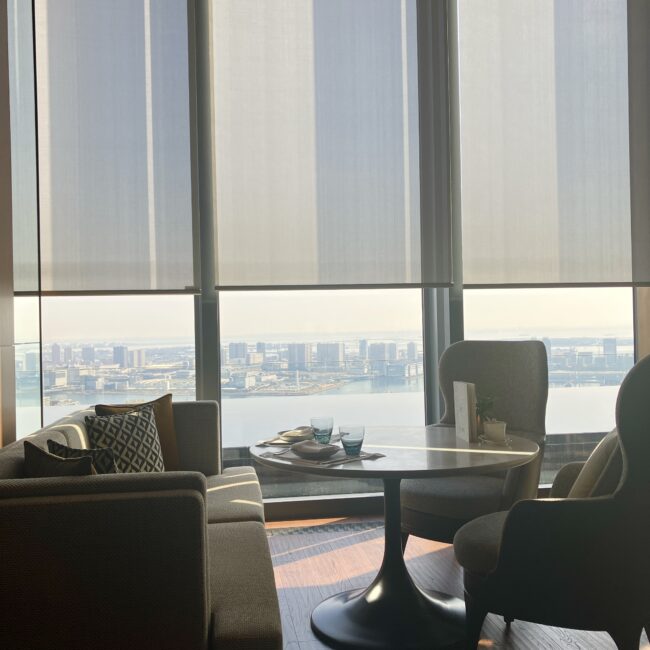 フェアモント東京の窓側席の様子。大きな窓からは東京湾の絶景が広がり、直射日光が差し込んでいるが、ロールスクリーンと高性能ガラスで快適さが保たれている。