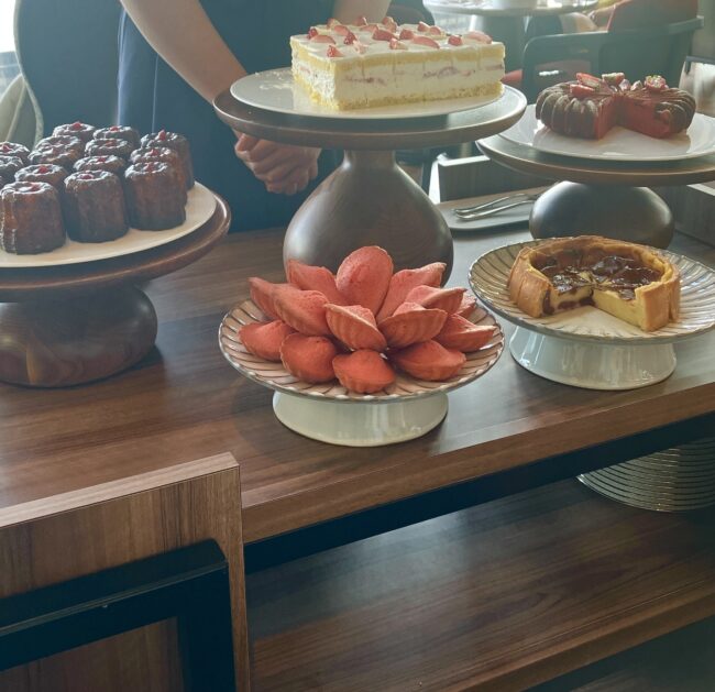 フェアモント東京のアフタヌーンティー名物、デザートワゴン。ホールサイズのいちごショートケーキやカヌレ、マドレーヌが並ぶ。 キャプション: 目の前でケーキがカットされる瞬間は、まさにエンターテインメント。ただし、ここで一つ重要な「掟」があります。