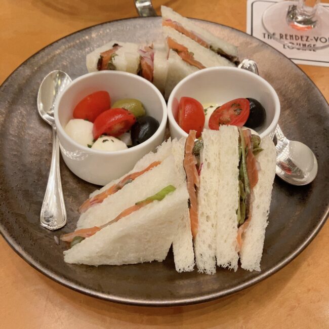 帝国ホテル「ランデブーラウンジ」アフタヌーンティーの2023年当時のセイボリー。白いパンを使用したサーモンサンドイッチと、小鉢に入ったトマト・モッツァレラ・オリーブのシンプルなマリネ。