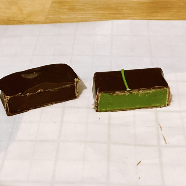 イナムラショウゾウのショコラ断面図。右:鮮やかな緑色の抹茶ガナッシュ、左:滑らかなダークガナッシュ。薄く均一なコーティング技術が光る