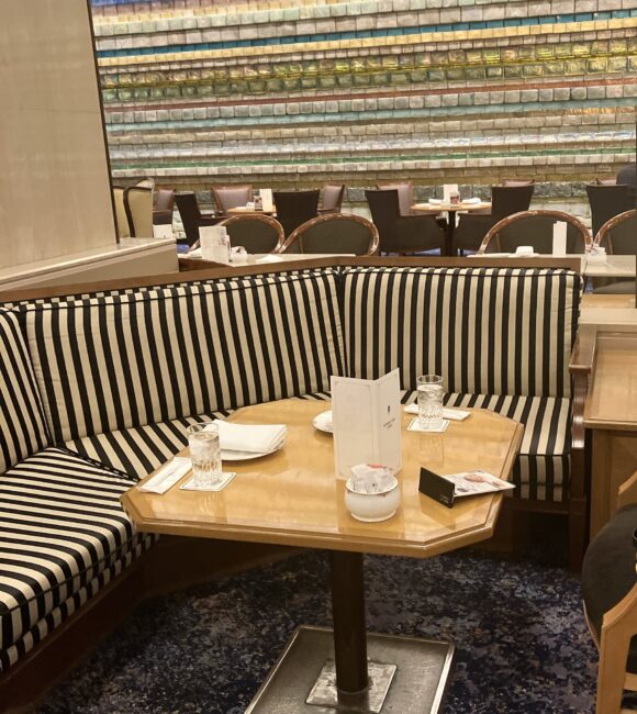 帝国ホテル ランデブーラウンジで案内された、ストライプ柄のゆったりとしたソファ席。奥には光の壁が見え、隣席との間隔が広い落ち着いた空間。