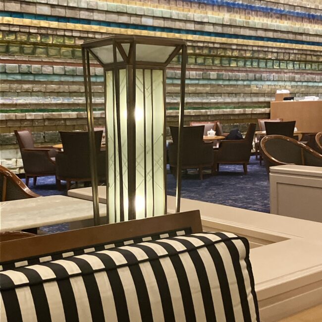 帝国ホテル ランデブーラウンジの座席から望む「光の壁」。アール・デコ調のレトロなテーブルランプ越しに、約7,600個のガラスブロックが壁一面に煌めいている様子。