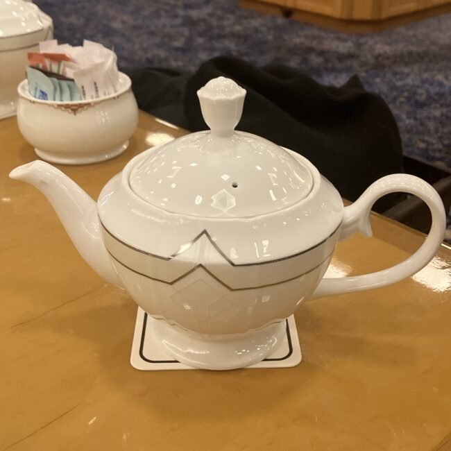 帝国ホテルの白いティーポットの蓋のアップ。持ち手（つまみ）の部分が、薔薇の蕾のような花のモチーフになっている。