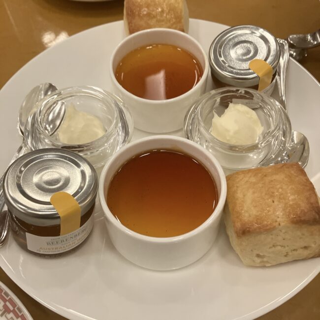 帝国ホテル アフタヌーンティーの中段プレート。四角いプレーンスコーン、クロテッドクリーム、瓶入りの蜂蜜と苺ジャム、プリンが載っている。