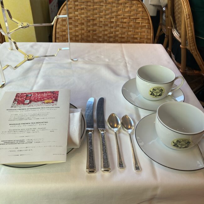 テーブルにセットされたマリアージュフレールのロゴ入りティーカップ2客と、シルバーのナイフ・スプーン。左側には「サクラ、サクラ!2026」の特別なメニュー表が置かれている。