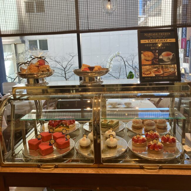 マリアージュフレール銀座松屋通り店のケーキショーケース。上部にはテイクアウト（持ち帰り）用の焼き菓子セットが陳列されている