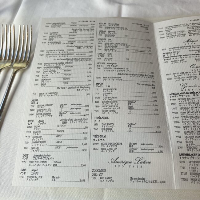 マリアージュフレールの分厚い紅茶メニューの中ページ。日本語、英語、フランス語でびっしりと数百種類のお茶銘柄と説明文、そして「1,650円」などのポット価格が記載されている。辞書のような圧倒的な情報量。